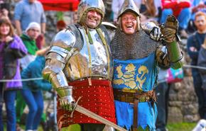 Two re-enactors dressed in knights clothing standing in front of crowd.